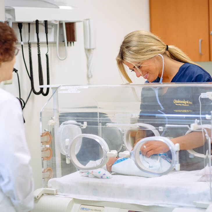 A nursing student tends to a newborn in a simulation lab.