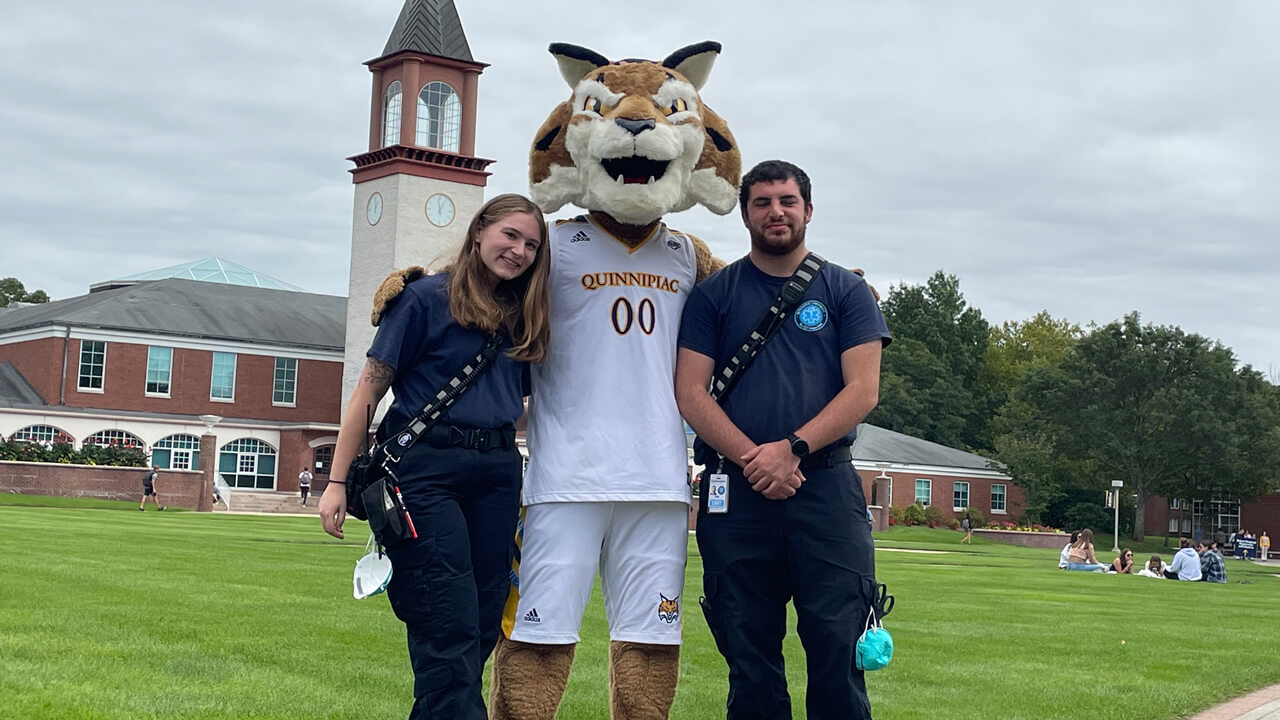 Two EMS students and Boomer the Mascot posing for a photo