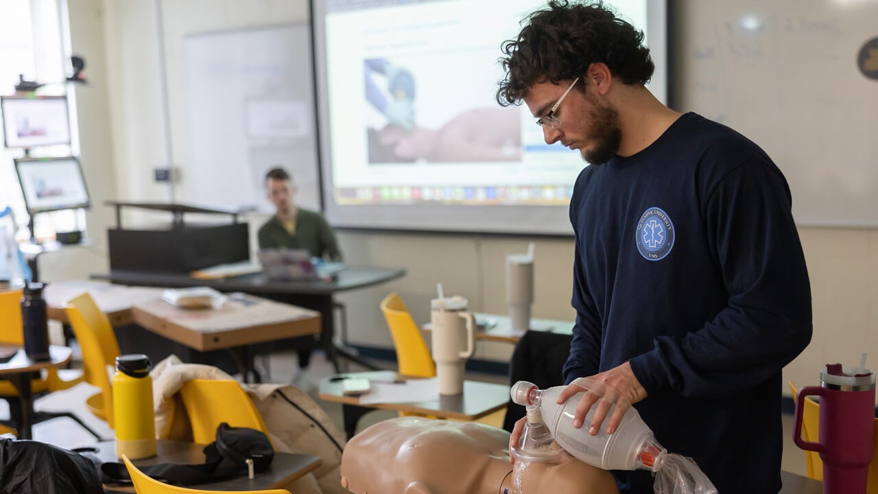 Student participating in CPR training on a dummy