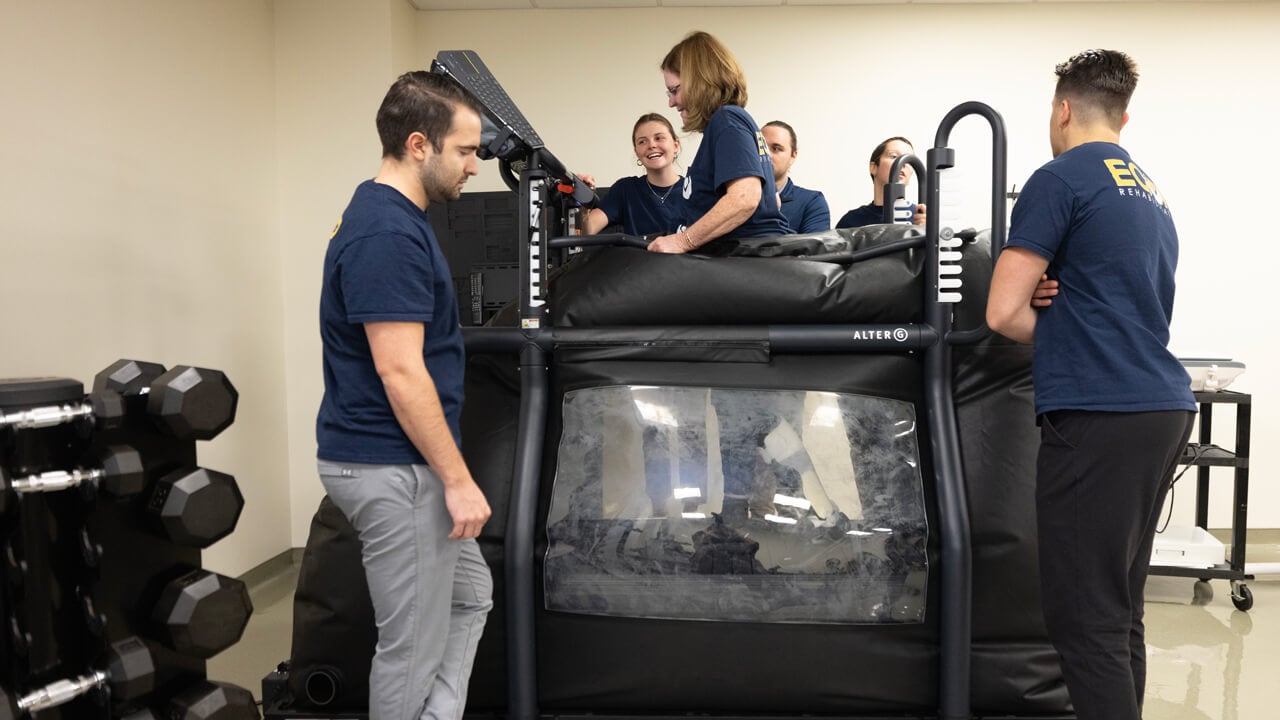 5 students watch a woman walking in a specialized treadmill