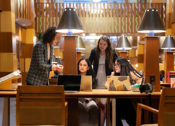 Women dressed up working in the School of Law library