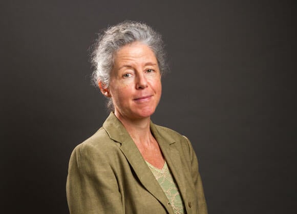 Elena Bertozzi smiles for a headshot wearing a green blazer.