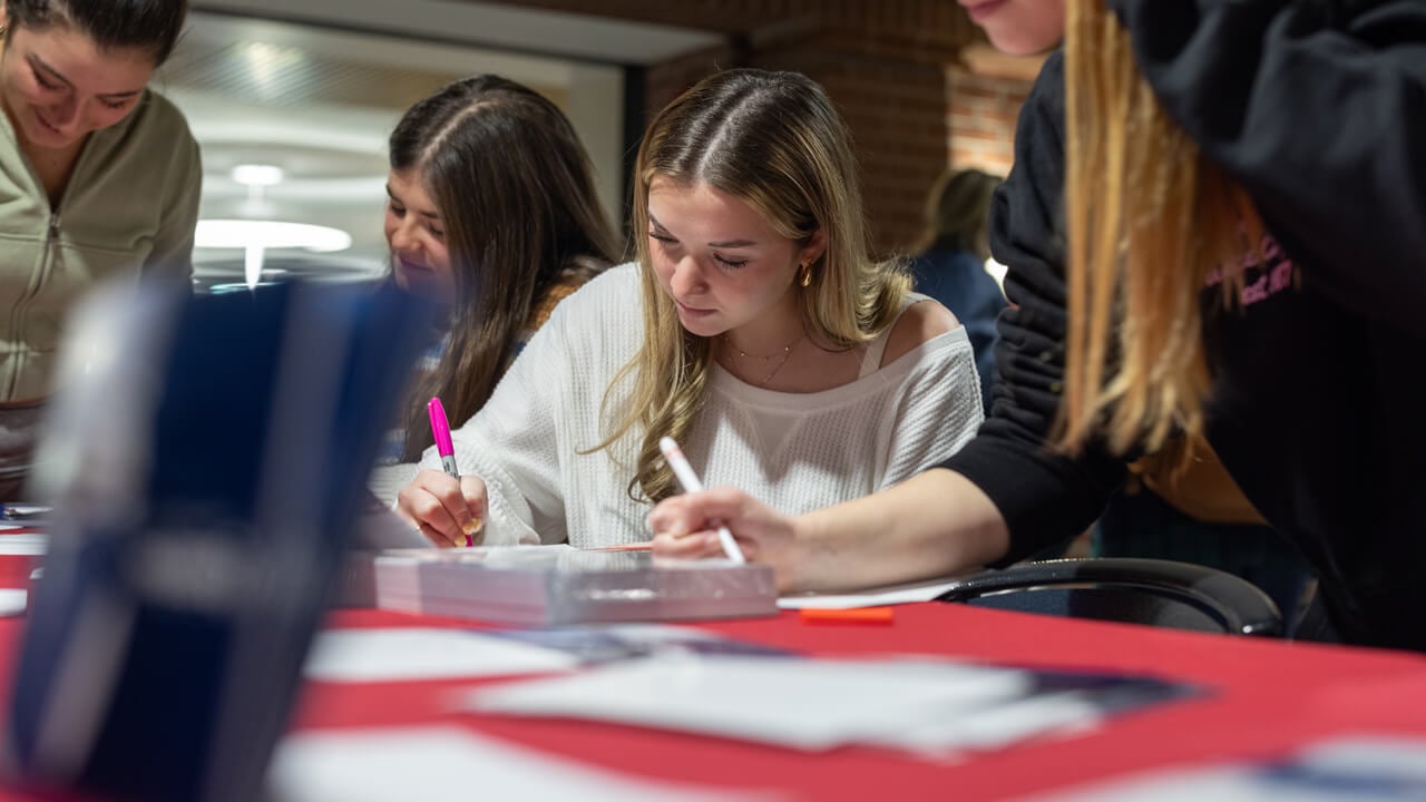 Individuals writing on cards