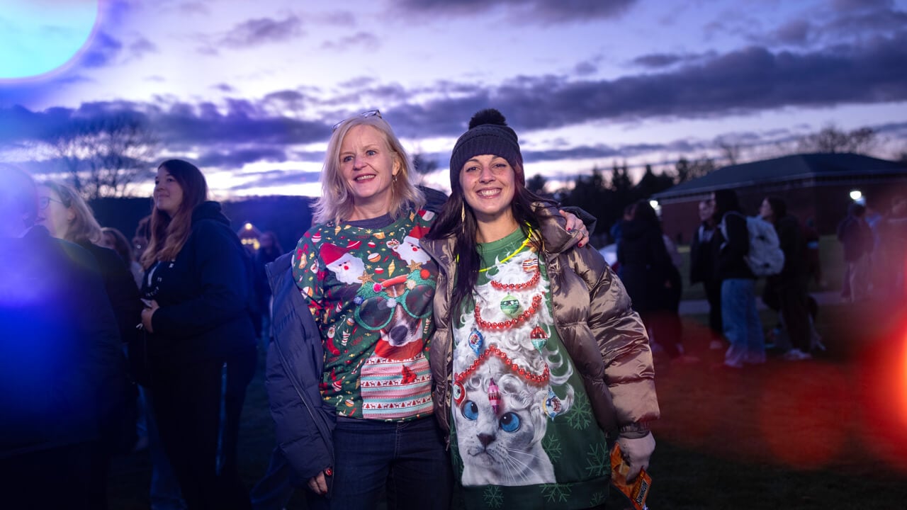 People pose for a photo with holiday lights