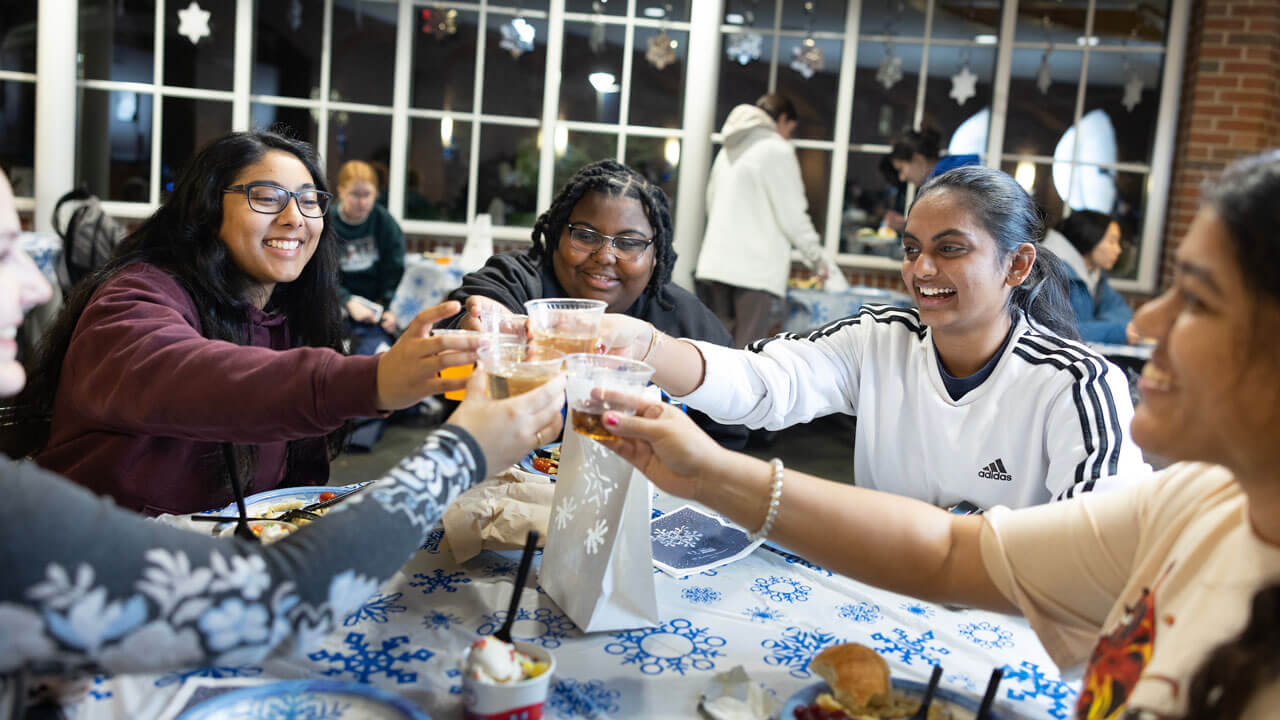 Students decorate ginger bread houses at undergraduate holiday dinner.