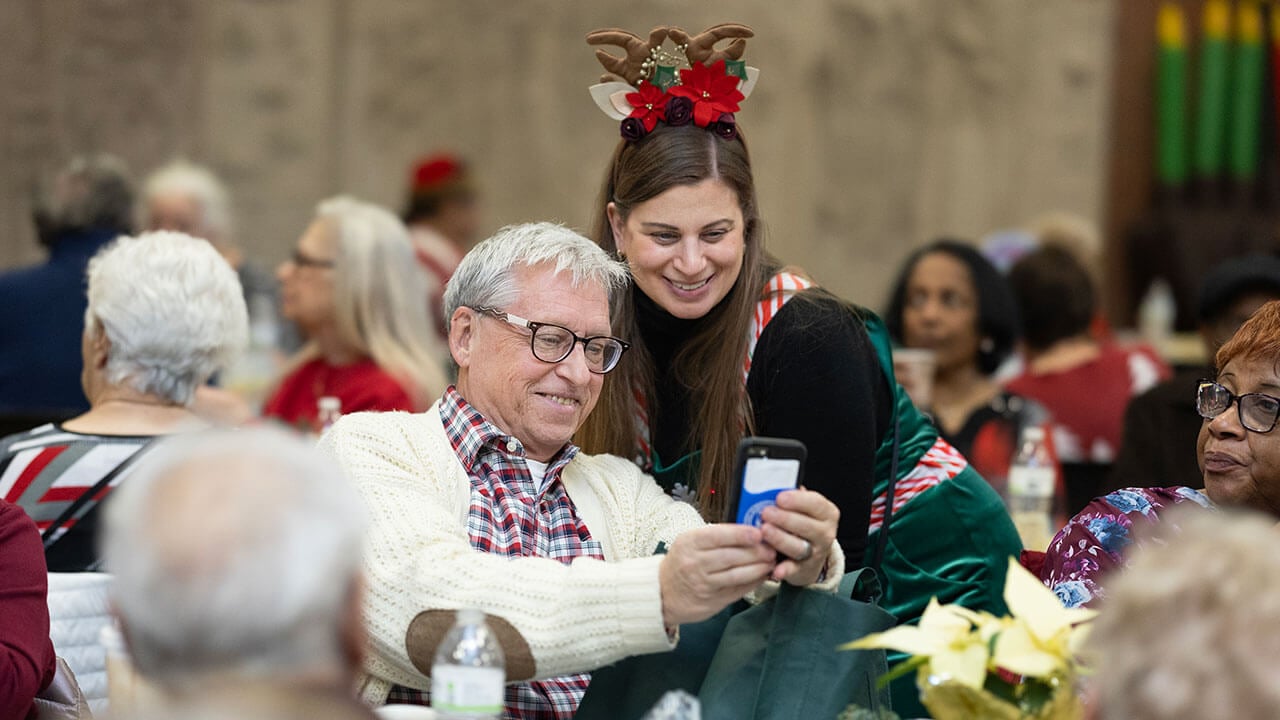 A senior citizen takes a selfie with another partygoer