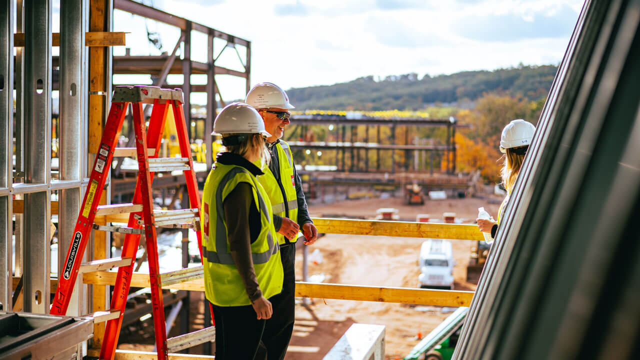 Construction workers talk to each other on the South Quad site.