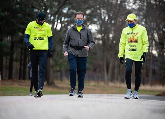 Two people escort a person walking with headphones