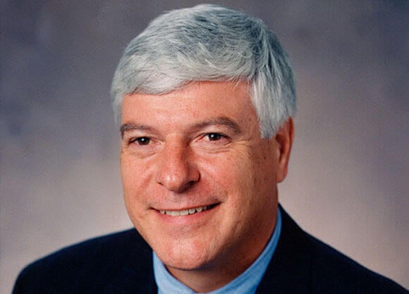 William Weldon smiles while wearing a suit.