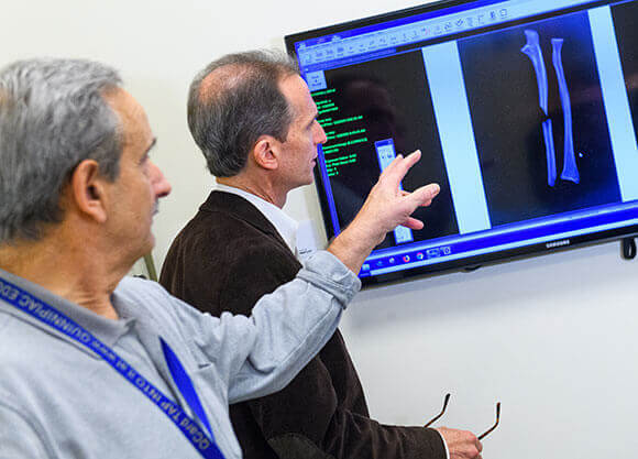 Robert Lombardo and another man look at a screen on the wall.