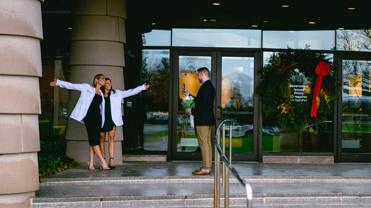 Two students posing in their white coats for a photo.