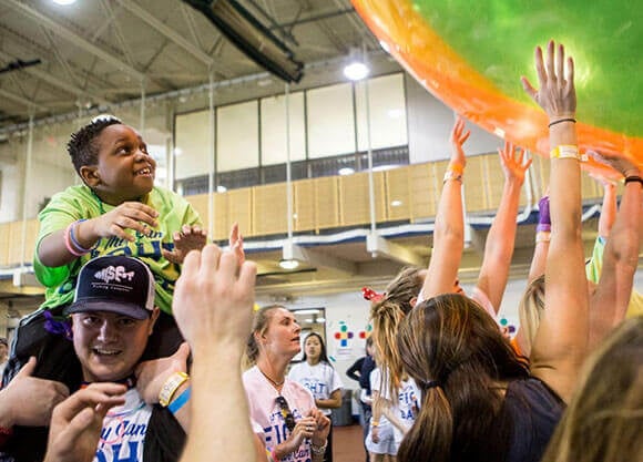 Students hold up a plastic ball as part of QTHON.