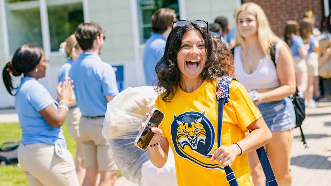 Student smiles and waves to the camera