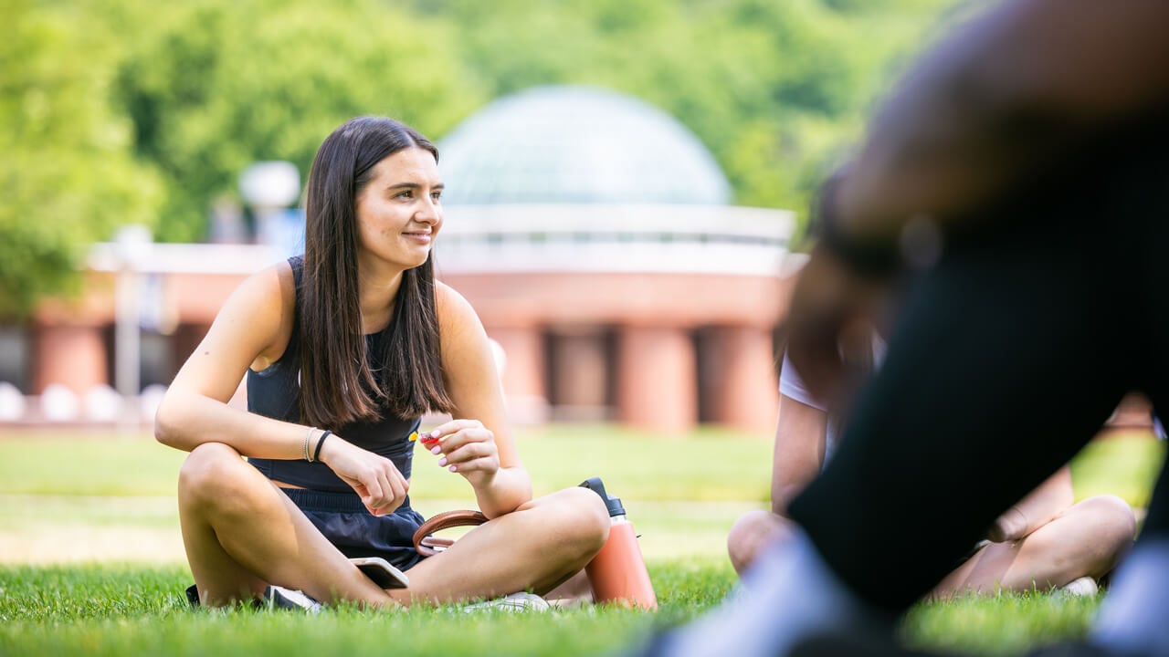 Student sits on the grass holding candy