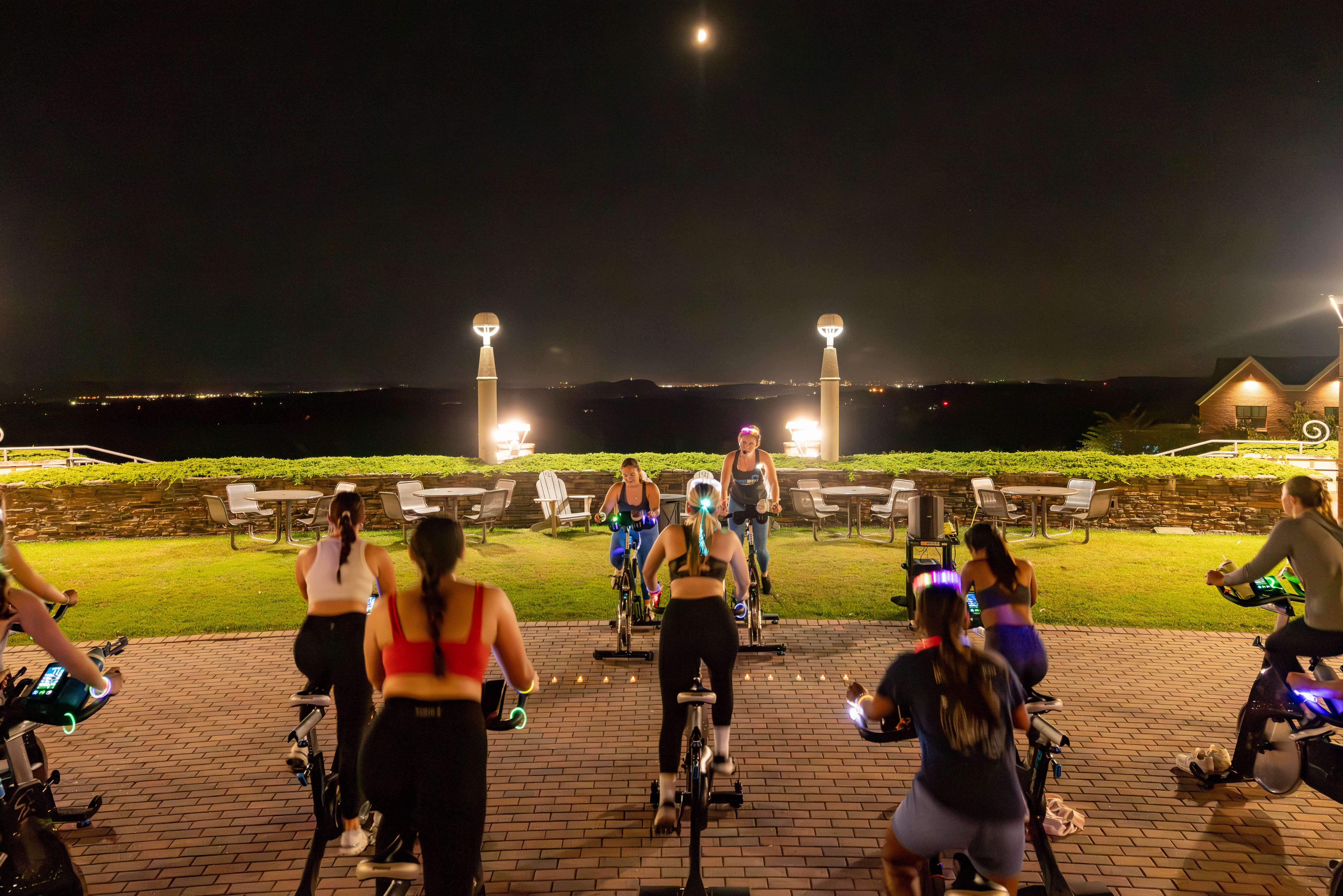 Students sit on stationary bikes outdoors