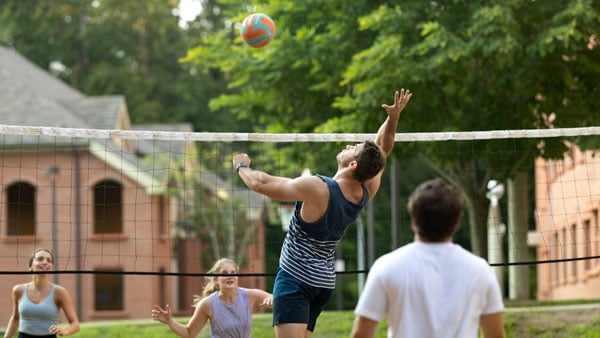 Student striking a volleyball over the net on the York Hill Campus volleyball nets