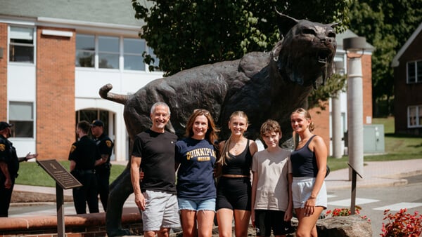 People pose in front of the bobcat statue