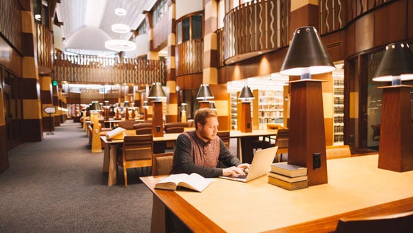 Student studying at a table in the beautiful Law Library located on the North Haven Campus