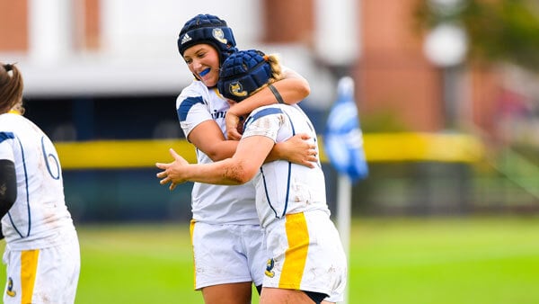 2 members of the women's rugby team celebrating with a hug