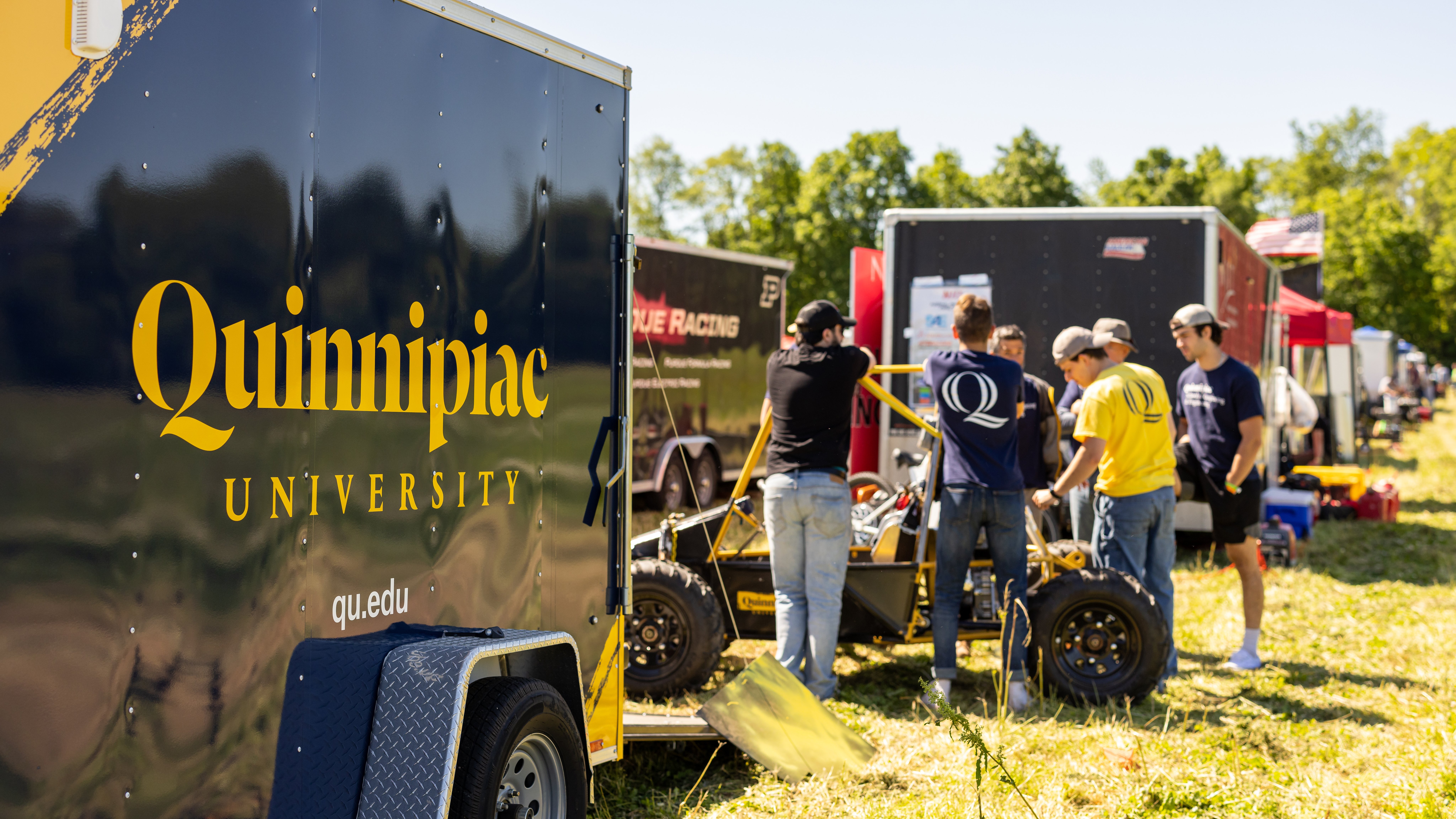 Students talk next to a vehicle