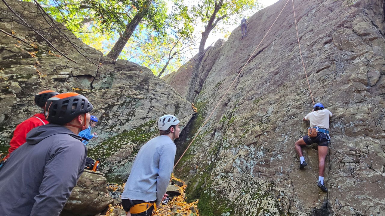 Students rock climb in a group