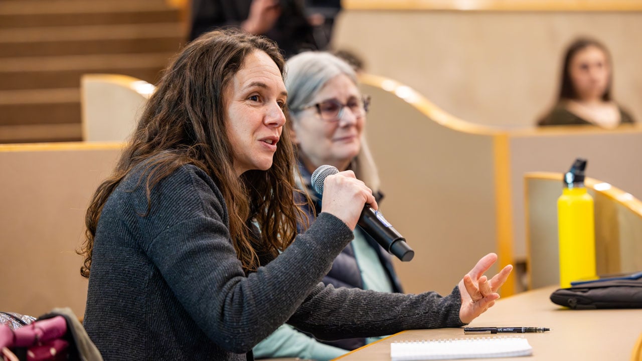 A woman in an audience speaking into a microphone