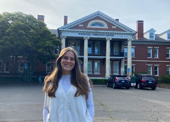 Student stands in front of brick building with columns which reads Burroughs Community Center