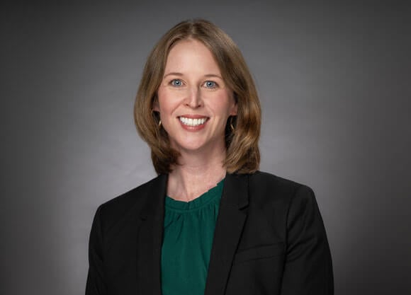 Kate Pfeiffer smiles with a grey background