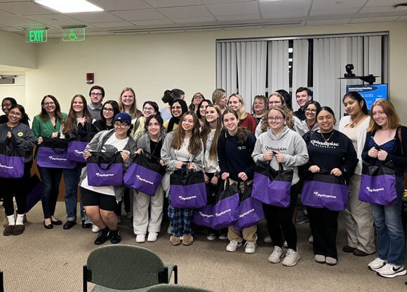 Students smile for photo holding tote bags.