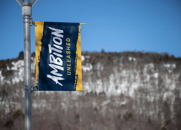 Ambition unleashed sign on the quad with the sleeping giant covered with snow in the background