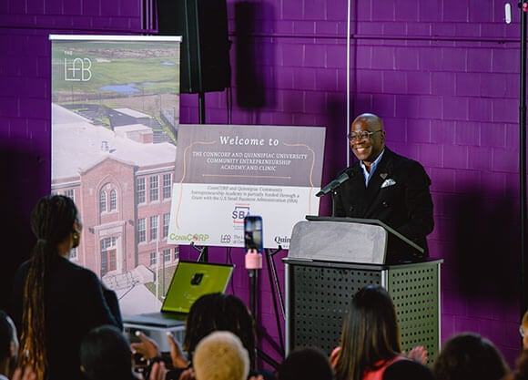 Board of Trustee Member Erik Clemons speaks to a crowd at ConnCORP