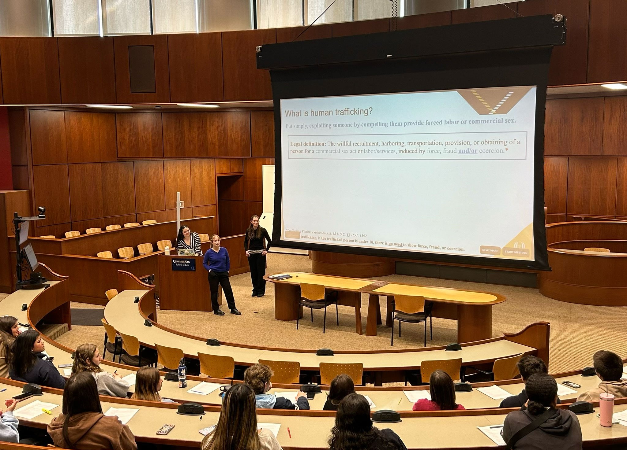 Three ladies presenting in a large auditorium to a crowd