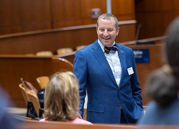 Dean Larry Slater enthusiastically talking to a colleague in the North Haven Campus ceremonial court room