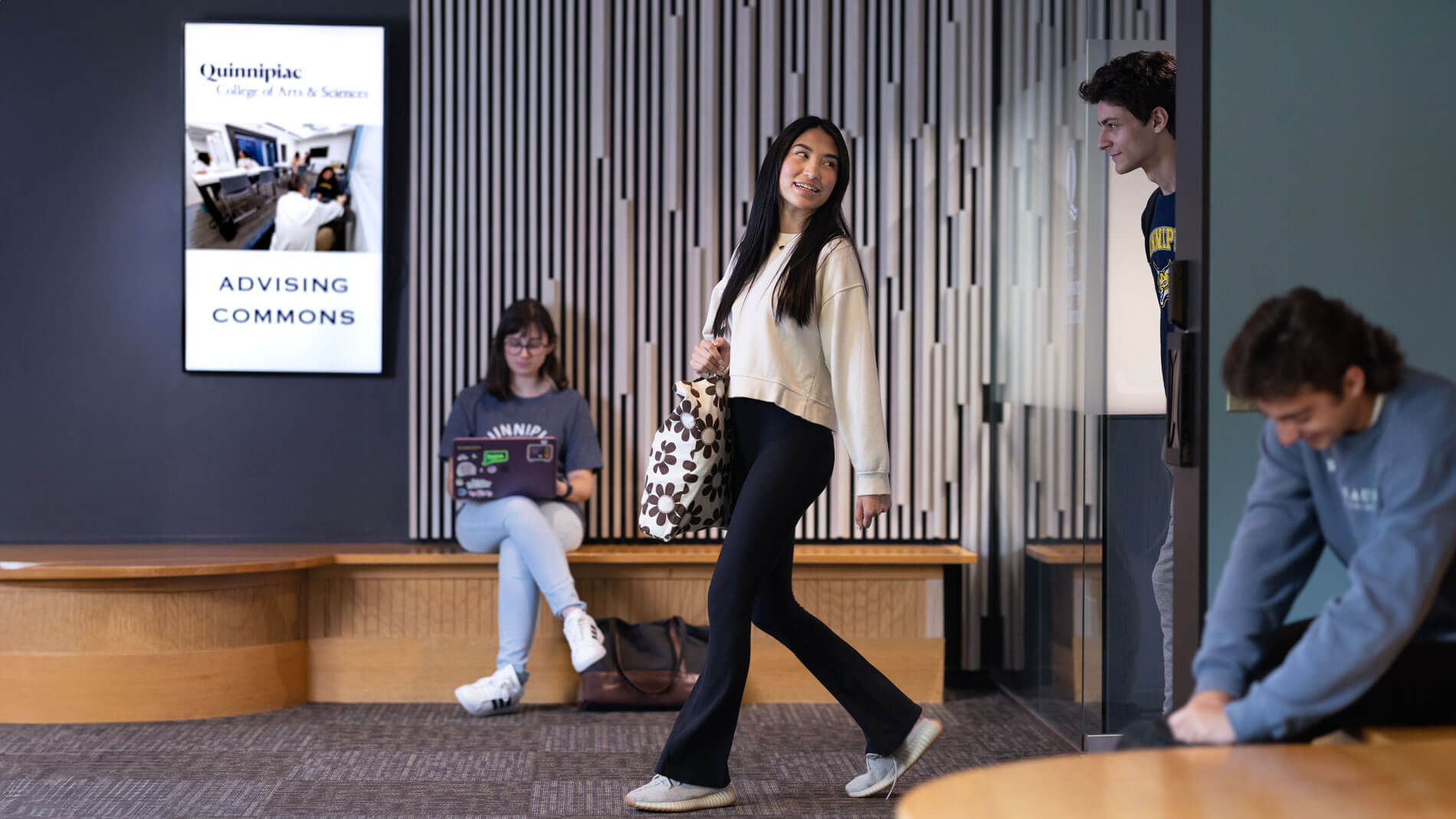 Quinnipiac students walk past the College of Arts and Sciences Advising Commons.