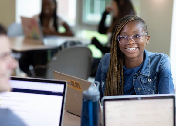 A business analytics student works collaboratively with laptops with another student