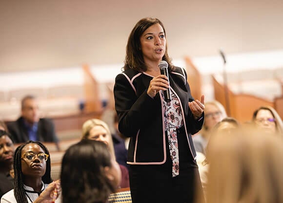 A student talks into a microphone in front of a group of people