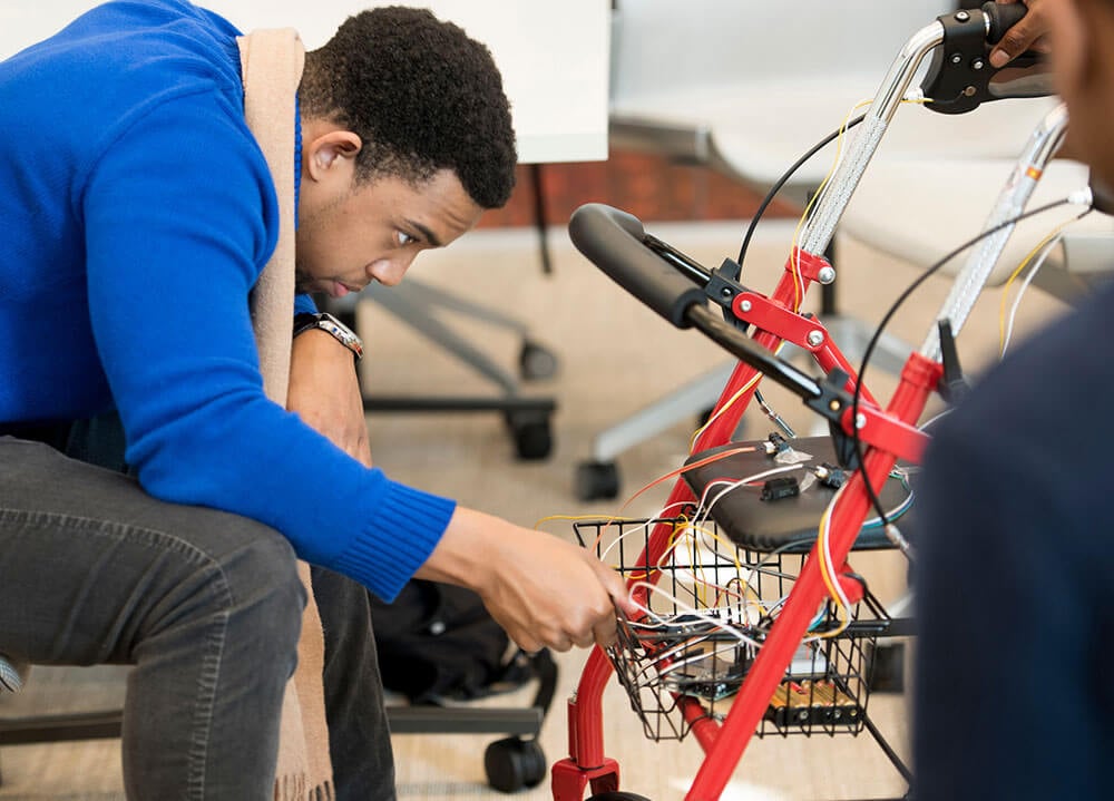 Student Nate Noncent works on the wiring of a responsive walker with wheels