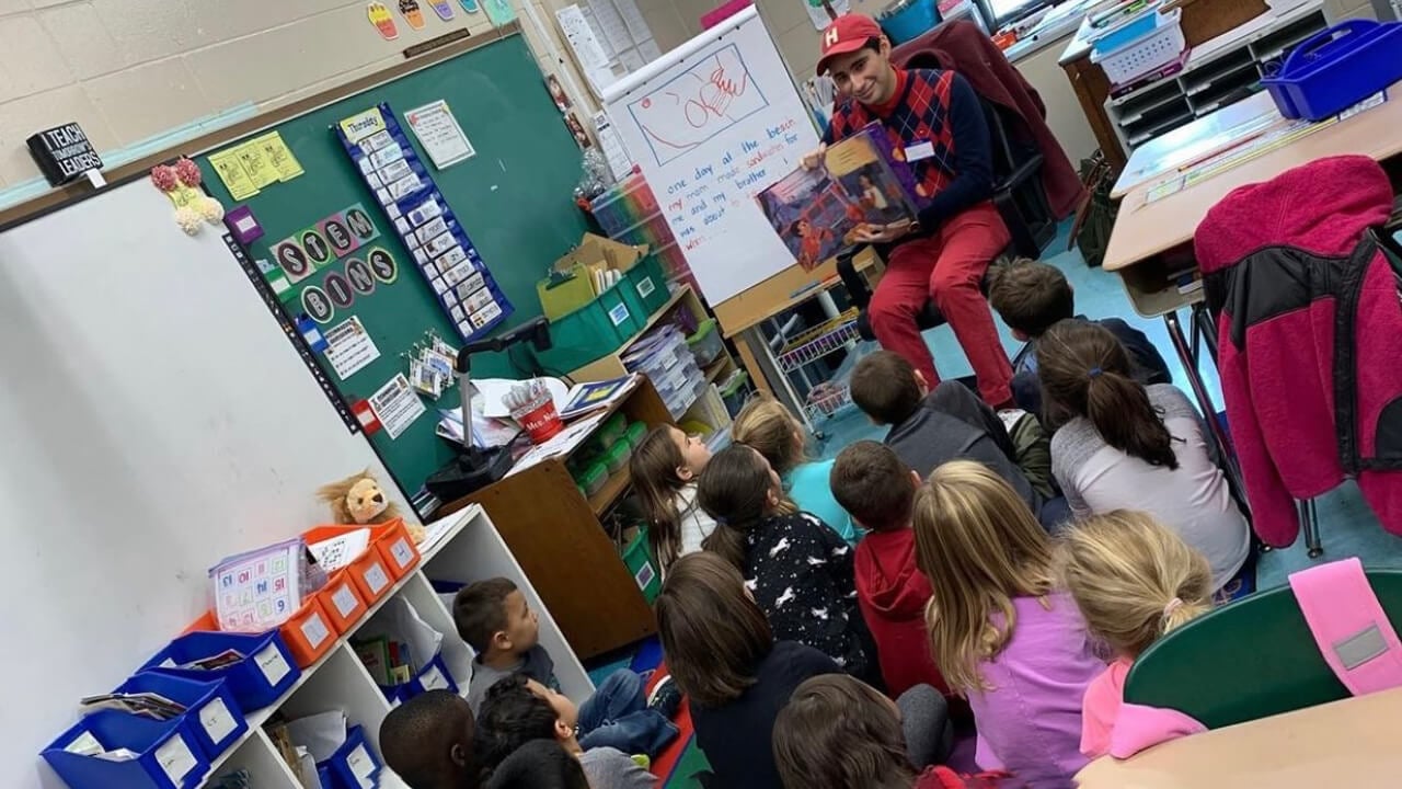 Quinnipiac University education student sits with kids in a classroom.