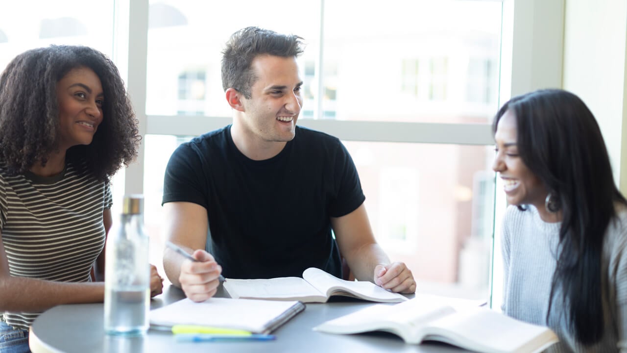 2 female and 1 male student studying together at a table