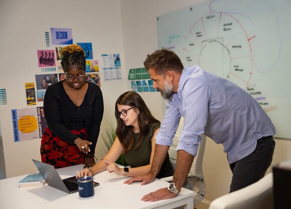 Graduate students and professionals collaborate on a laptop in an office