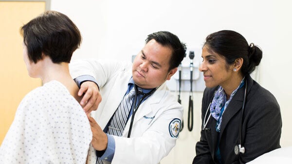 A medical student works with a professor on clinical skills