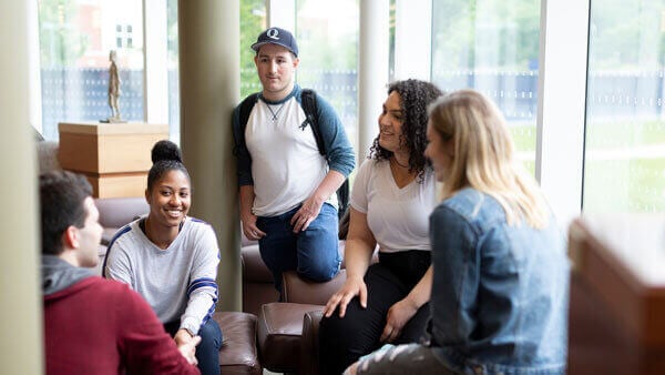 A group of undergraduate students talk together in the library