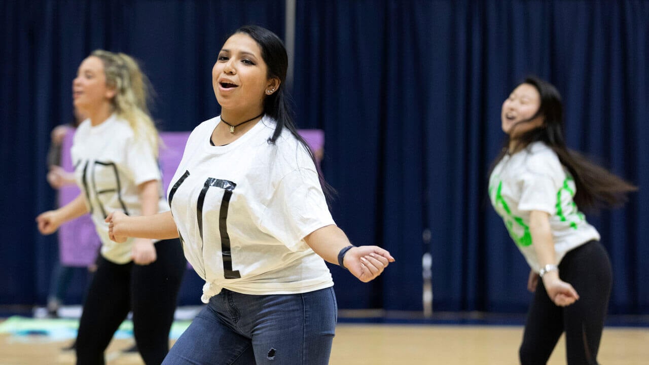 Three students performing a dance routine in the People’s United Center on the York Hill Campus