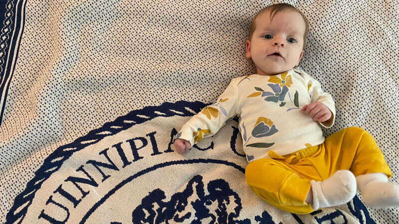 Baby laying on Quinnipiac blanket